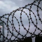 Drut kolczasty na tle pochmurnego nieba, symbol granic i ograniczeń